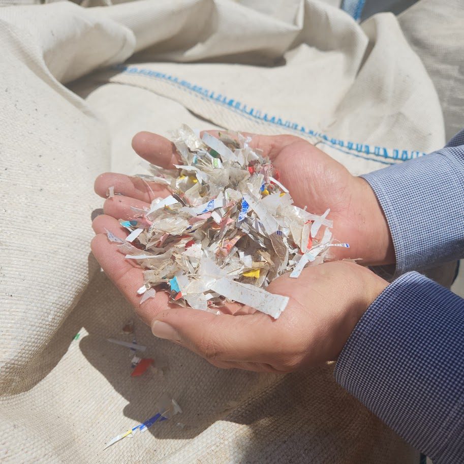 Mãos seguram plástico triturado sobre bag de material processado